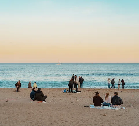People spending the evening on Barceloneta sand beside the Mediterranean.