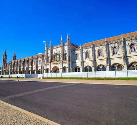 Jerónimos Monastery exterior beneath bright blue sky.