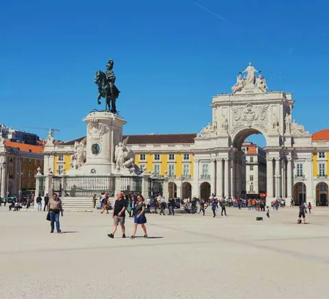 Praça do Comércio’s yellow arcades, triumphal arch and people on the square.