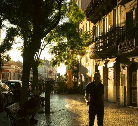 Pedestrian on Rua Dom Pedro V, Bairro Alto, in warm evening sunlight; source confirms street location.