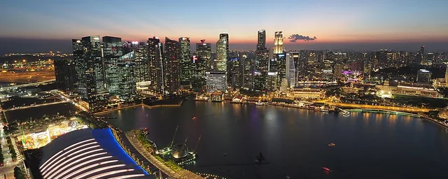 Marina Bay waterfront, illuminated financial skyline and water seen from Marina Bay Sands at blue hour.